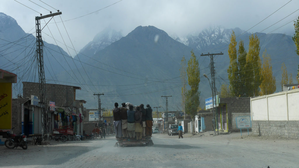 Men traveling on the back of a pickup truck