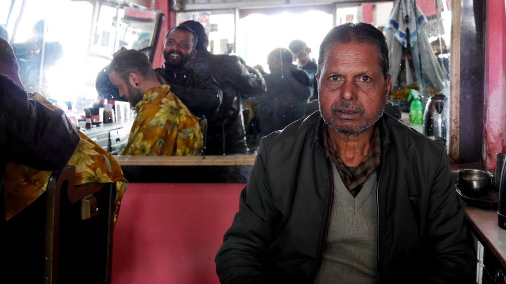 Owner of a barber shop in Namchi and Seri getting his hair cut